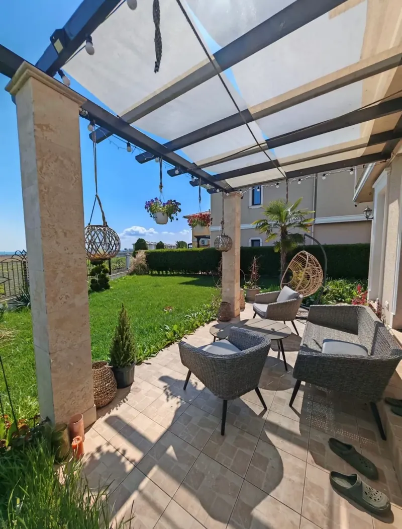 Terrace under the pergola with lounge furniture and hanging chair, villa in the Victoria Lakes quarter, Victoria development near Pomorie