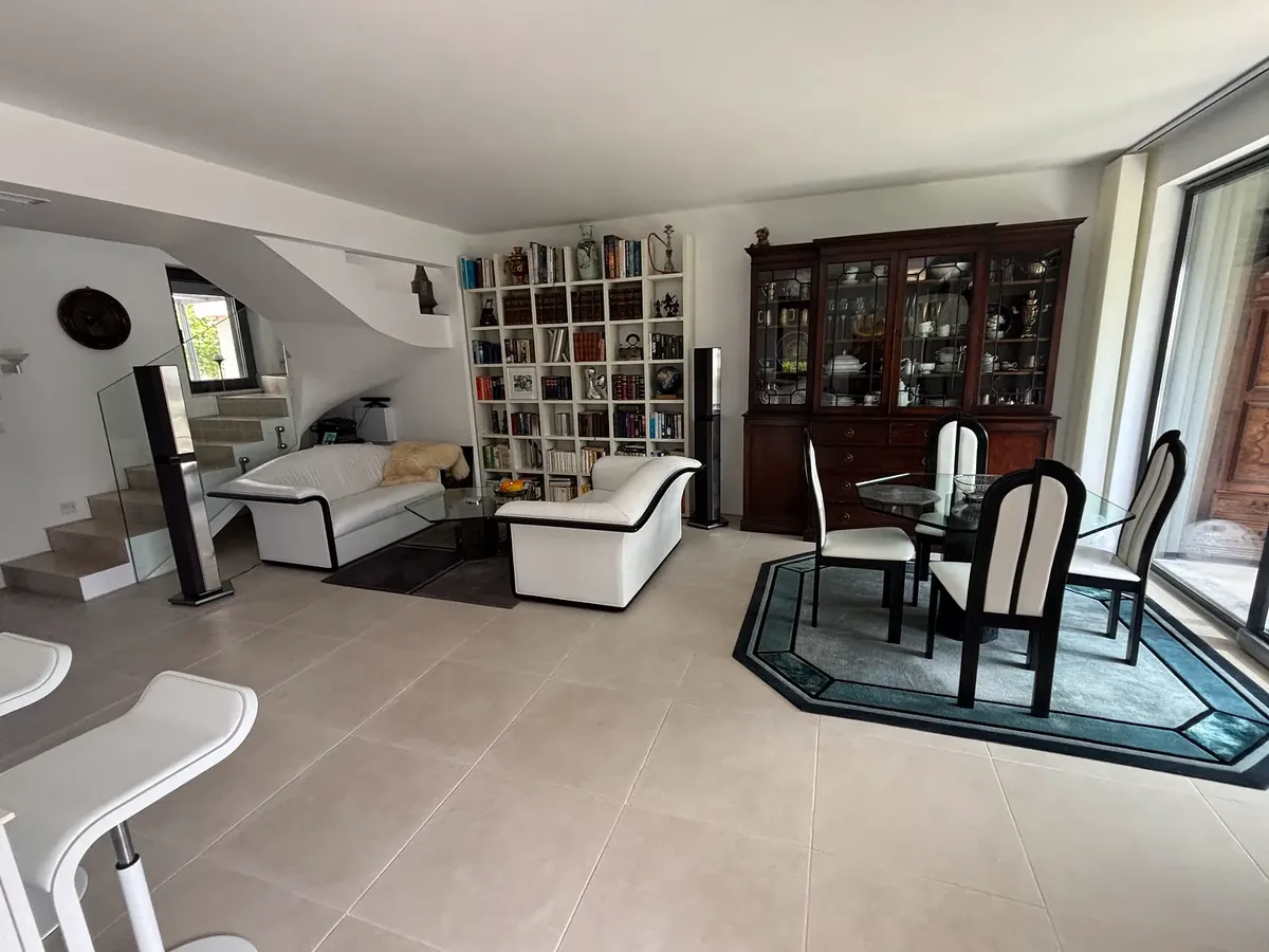 Open-plan living and dining area with sofas, bookcase wall and stairs, villa in the Victoria Sunrise quarter, Victoria development near Pomorie