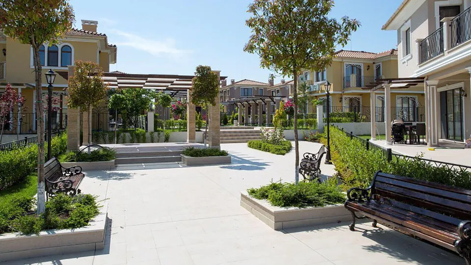 Square with benches, pergolas and lanterns between the villas